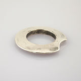 Abgenutztes silbernes Objekt in Ringform mit kleiner Kerbe auf weißem Hintergrund