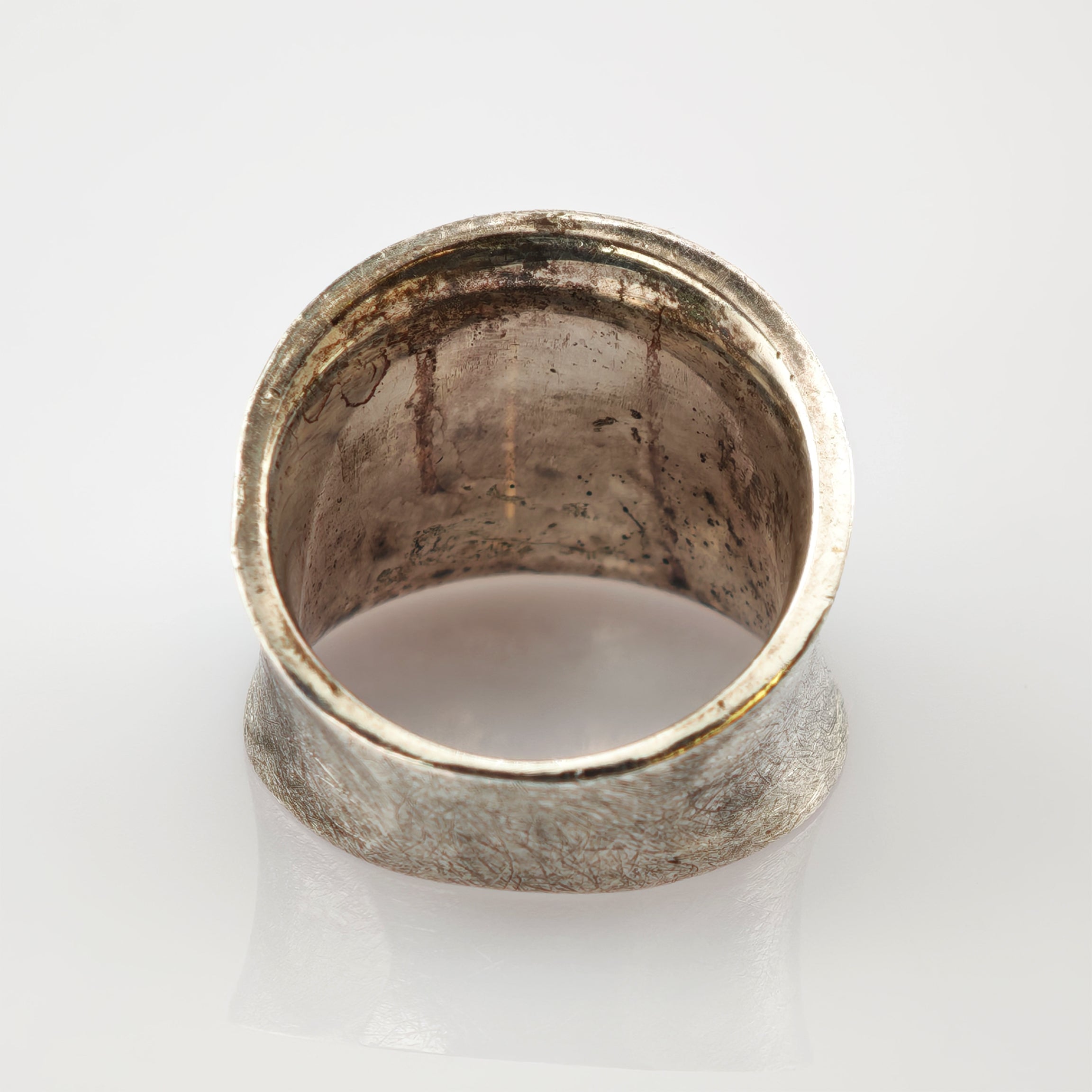 Nahaufnahme eines alten silbernen Rings mit breitem Band und sichtbarer Patina auf weißem Hintergrund