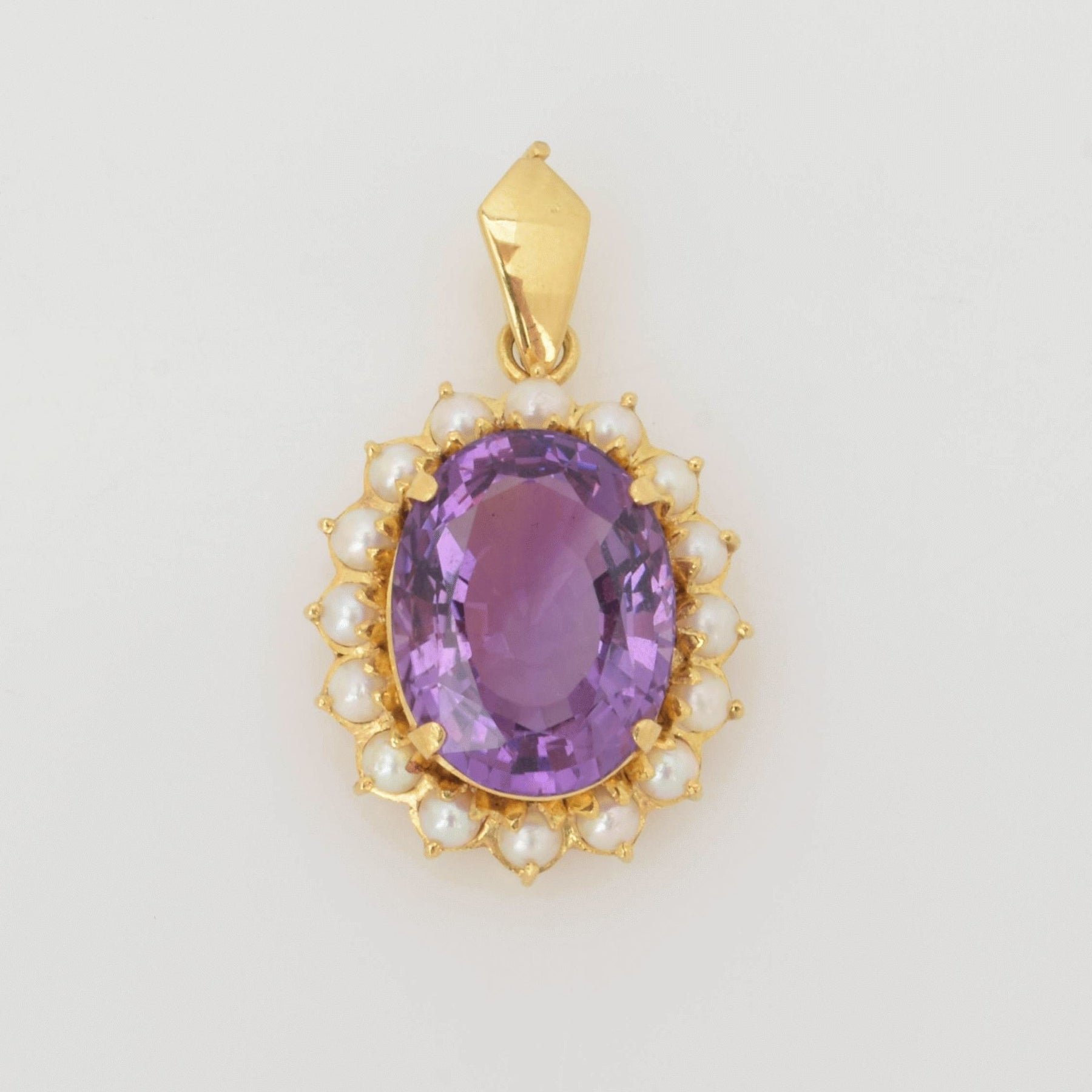 Anhänger mit facettiertem ovalem lila Edelstein und weißen Perlen im goldenen Rahmen