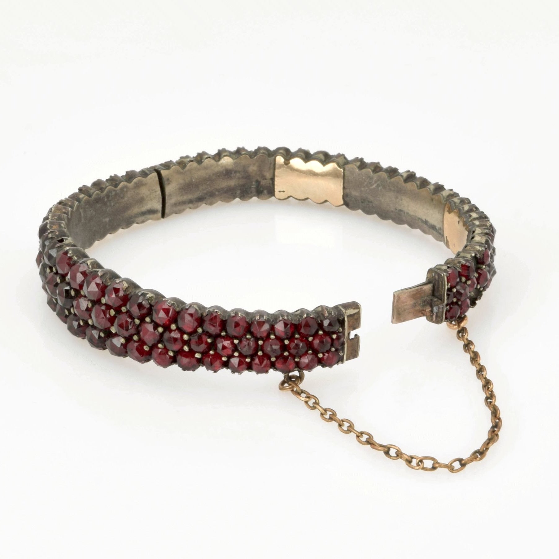 Antiker Armband mit drei Reihen tiefroter Edelsteine auf oxidiertem Metallsockel und kleiner Sicherheitskette.