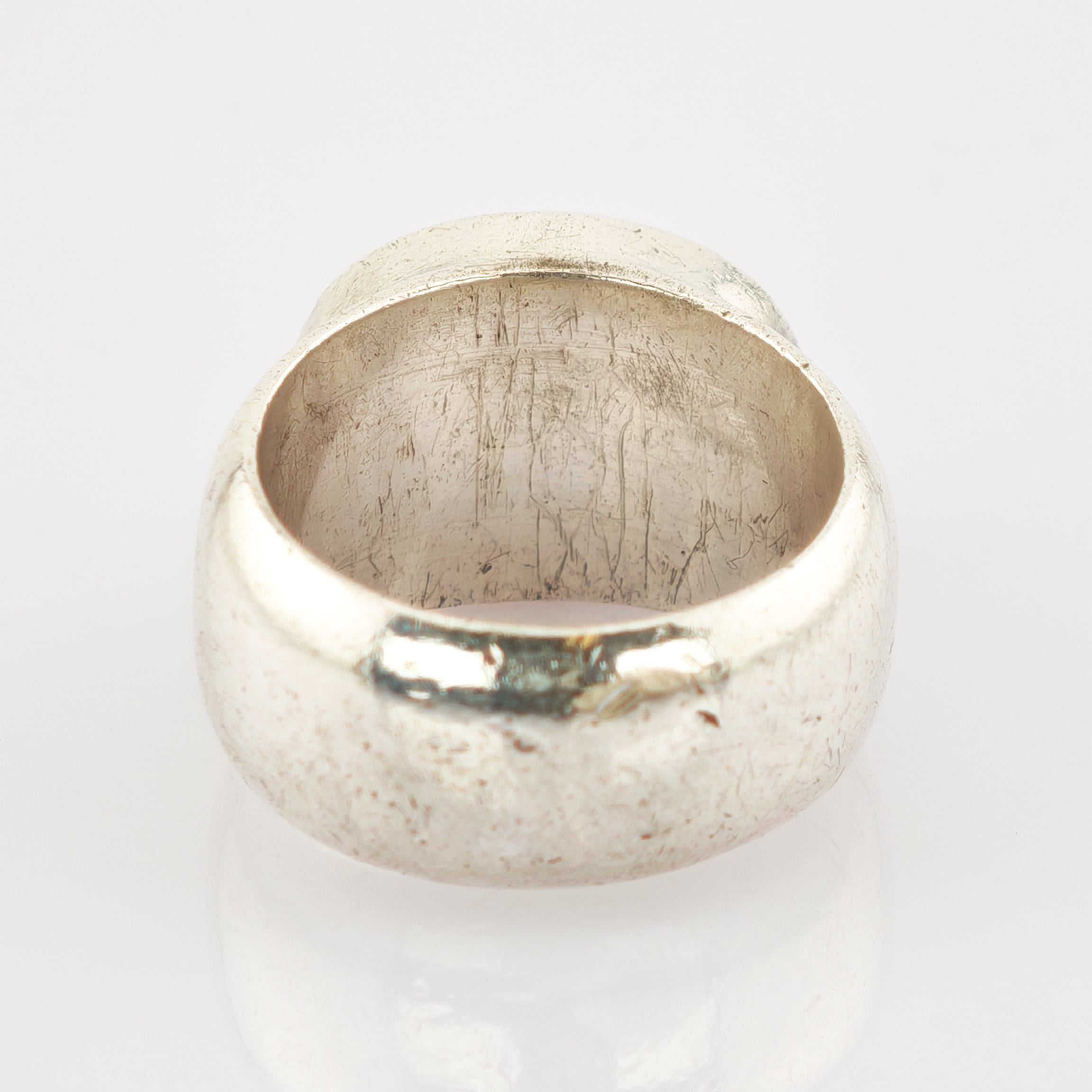 Antiker Metallring mit abgenutzter Oberfläche auf reflektierendem Weiß