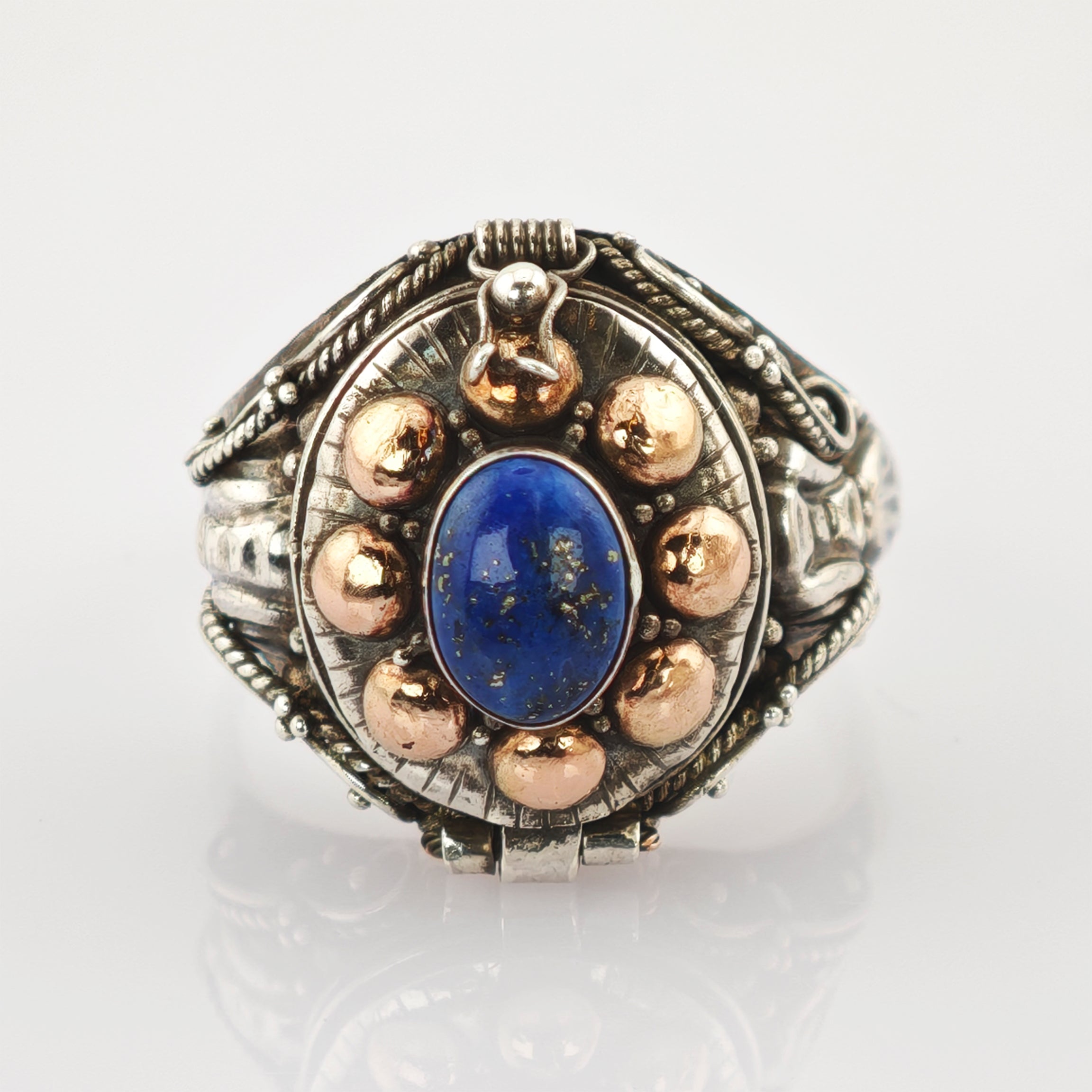 Antiker Ring mit ovalem blauen Edelstein, umgeben von goldenen Kugeln und filigranen silbernen Verzierungen.