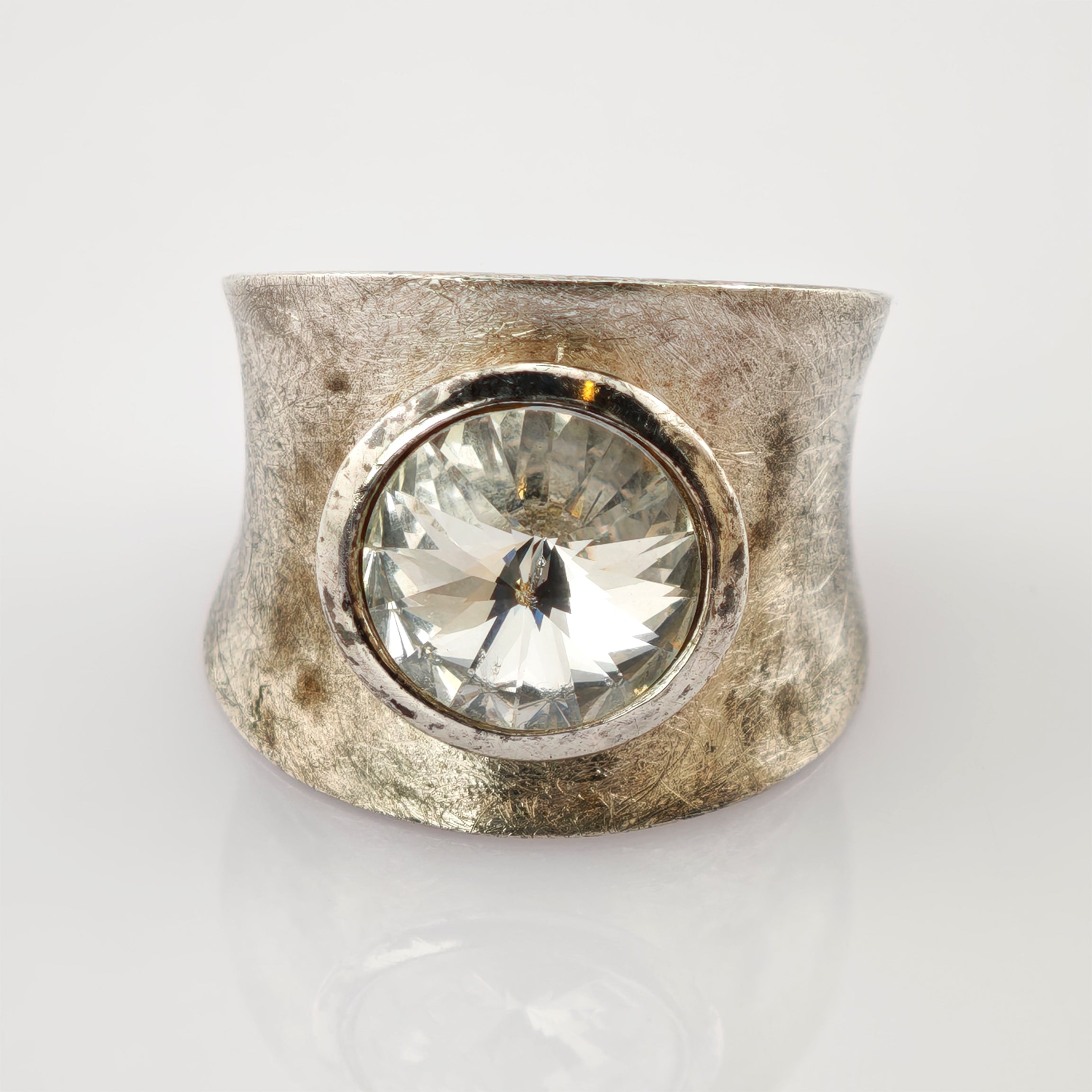 Breiter Silberring mit strukturierter Oberfläche und großem klarem facettiertem Edelstein.