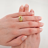 Zwei elegante Frauenhände mit nude rosa Maniküre und Goldring mit ovalem gelbem Edelstein und kleinen Diamanten.