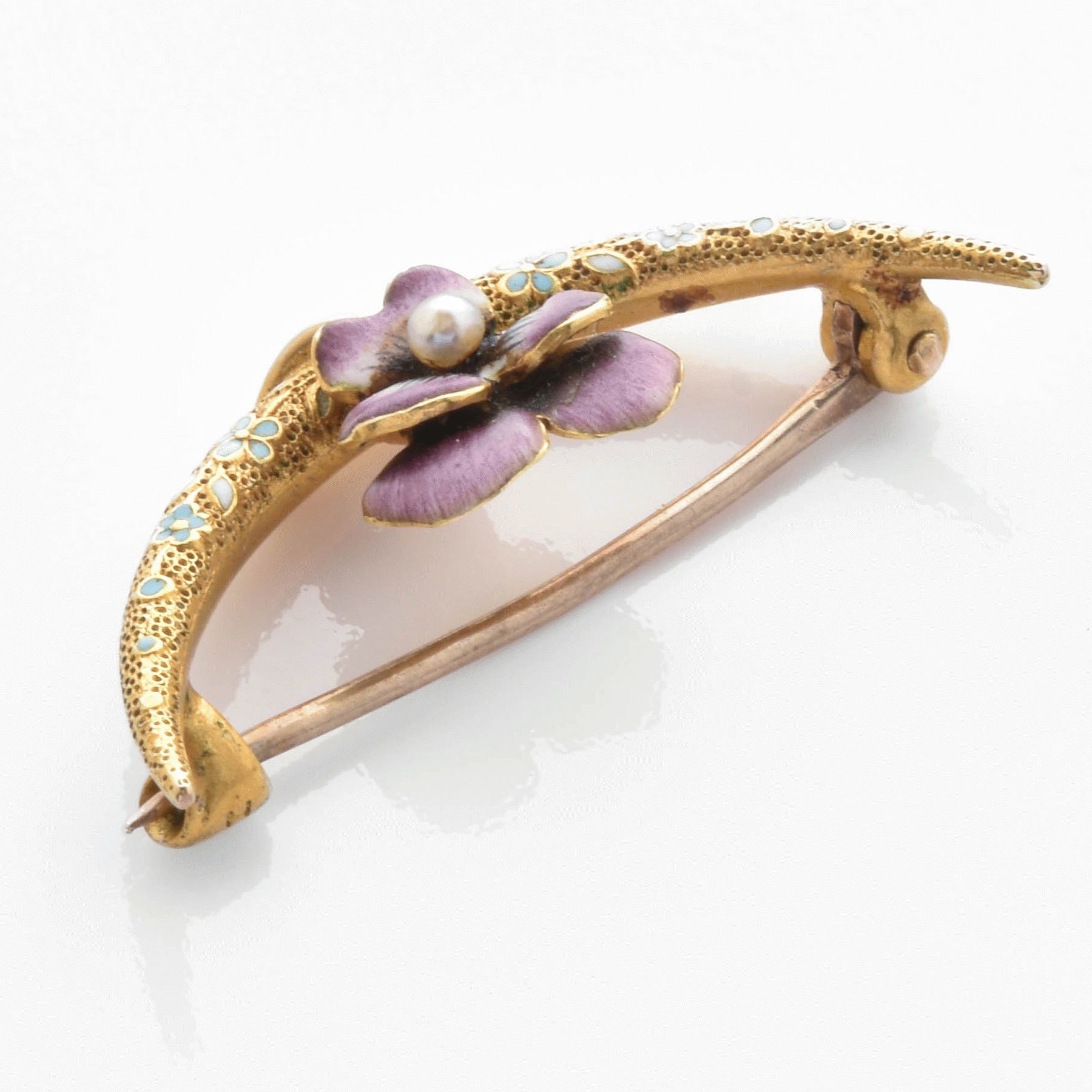 Elegante Sicherheitsnadelbrosche in Gold mit blauen und weißen Emaille-Blumenmustern und lila Blume mit Perle.