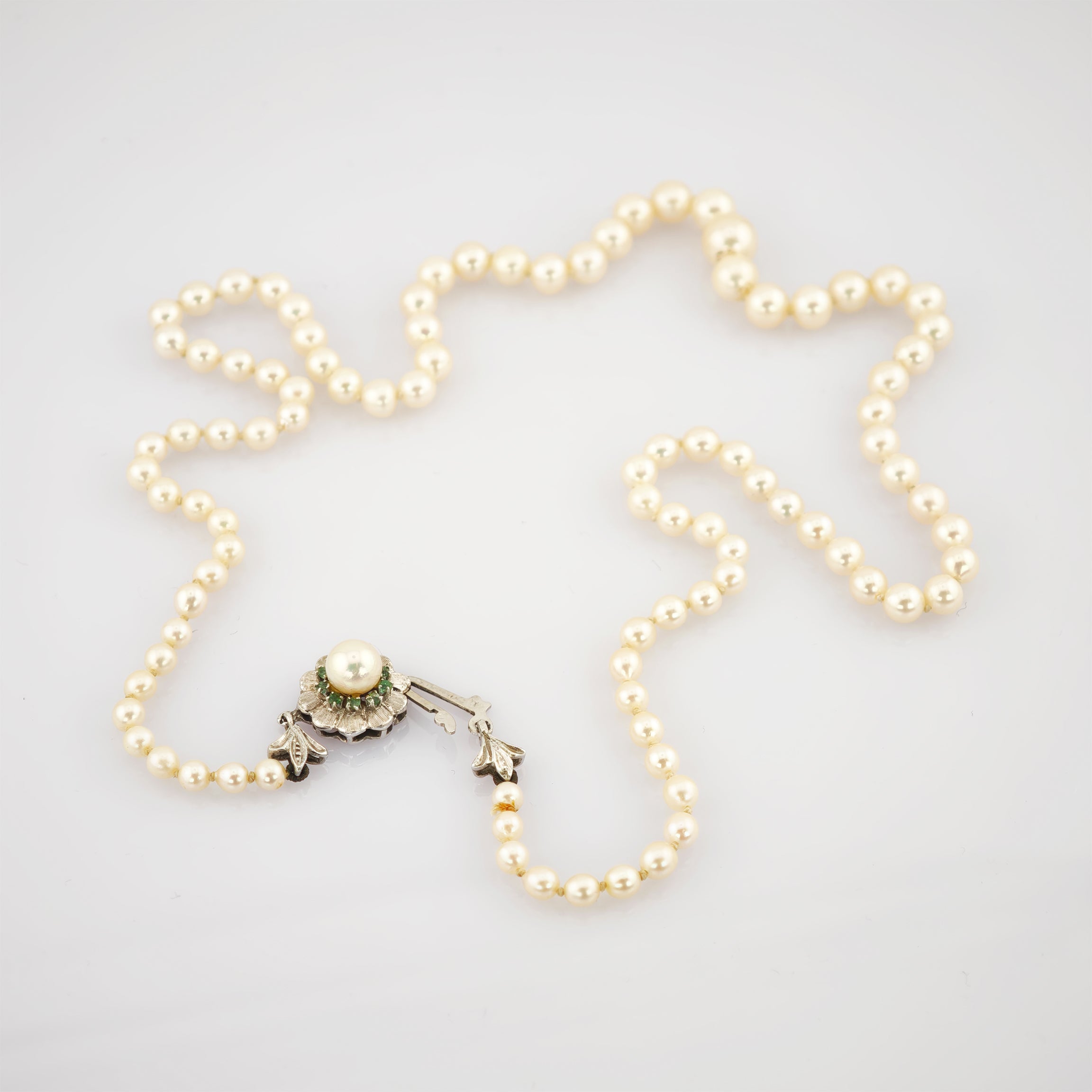 Elegante Perlenkette in Sternform mit cremefarbenen Perlen und verziertem Metallschloss.