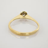Eleganter Goldring mit kleinem Diamanten im minimalistischen Design auf hellgrauem Hintergrund.