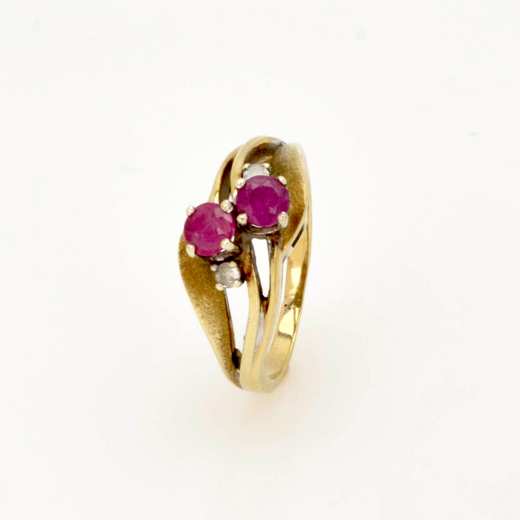 Eleganter Goldring mit zwei runden pinken Edelsteinen und kleinen klaren Steinen auf kunstvoll gewellten Bändern.