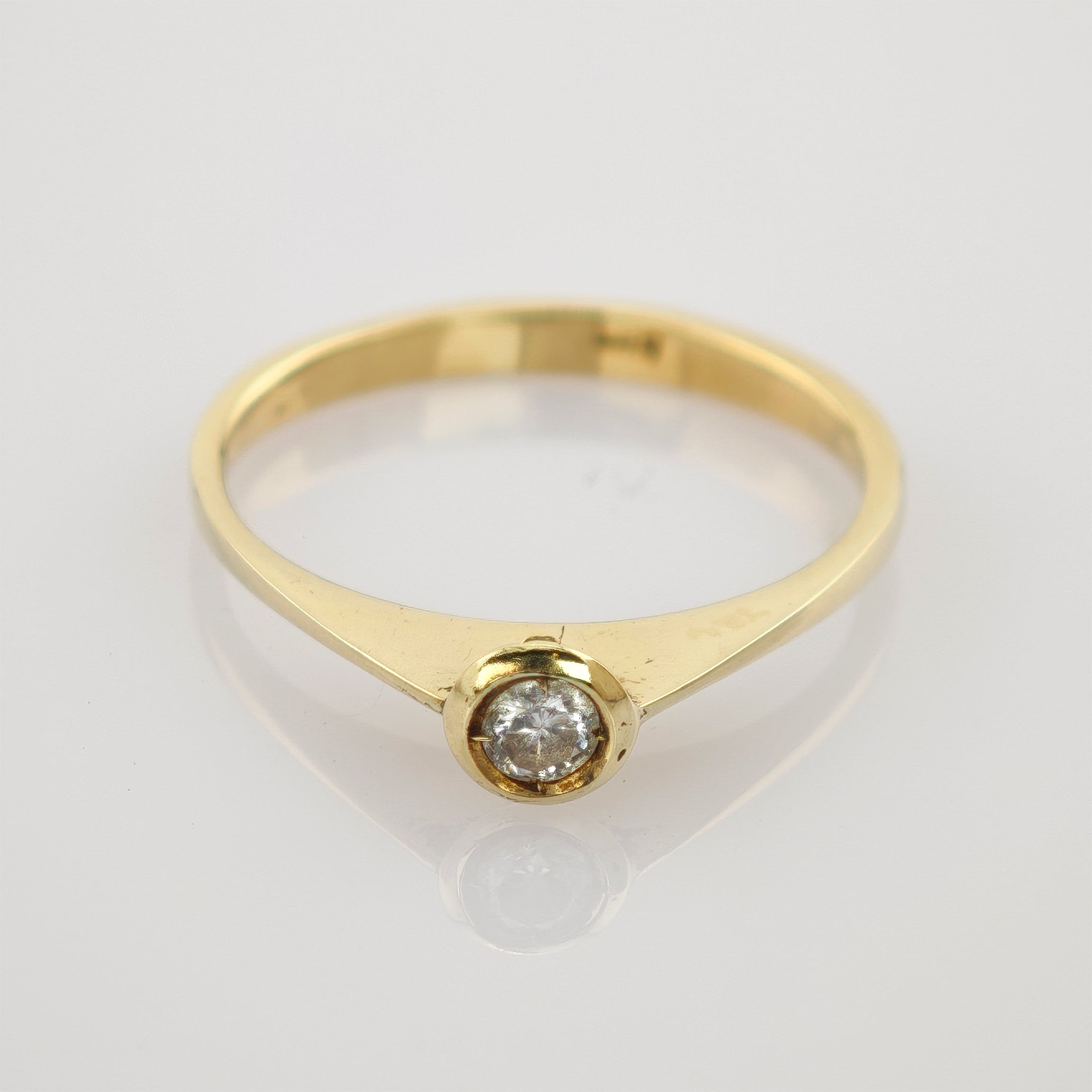 Eleganter Goldring mit rund geschliffenem Diamant in Fassettensitz auf weißem Hintergrund.