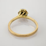 Eleganter Goldring mit schlanker Bandschiene und erhöhter Fassung für einen Edelstein auf weißem reflektierendem Untergrund.