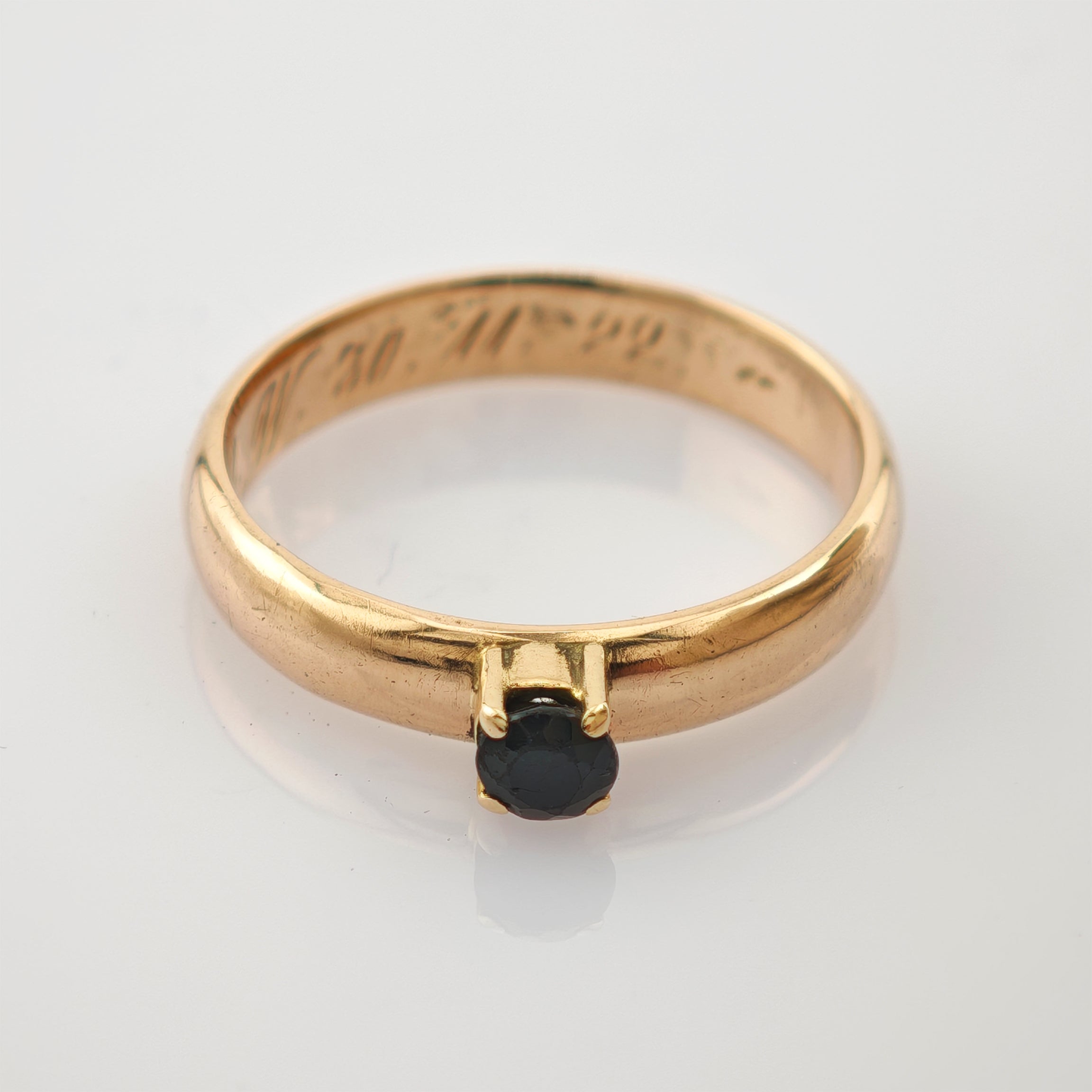 Eleganter Goldring mit glattem Band und kleinem rundem schwarzen Stein in Vierkrappefassung, Gravur W3099 innen.