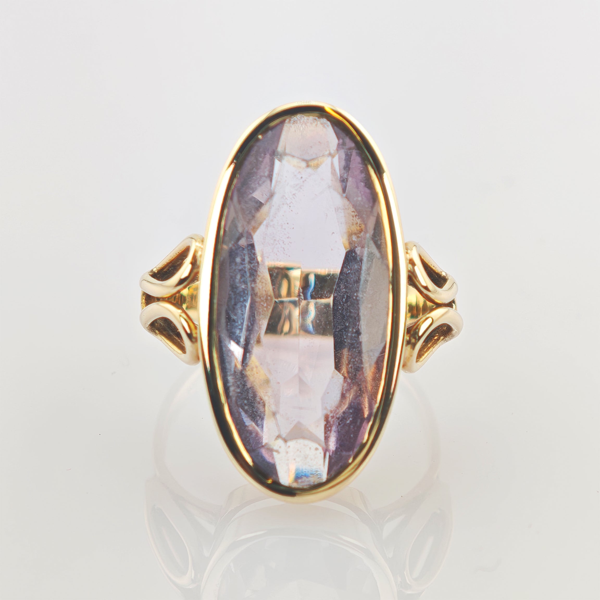 Eleganter Goldring mit großem, vertikal ovalem violettem facettiertem Edelstein und kunstvollen Metallverzierungen
