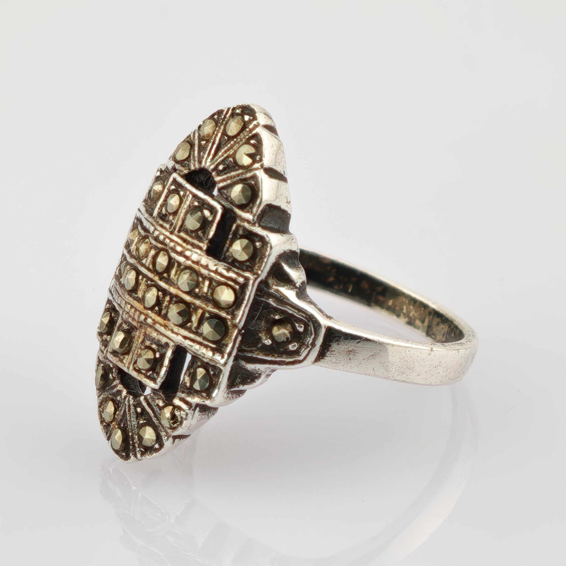 Eleganter silberner Ring mit ovalem Oberteil und geometrischen Mustern, verziert mit Metallnieten.
