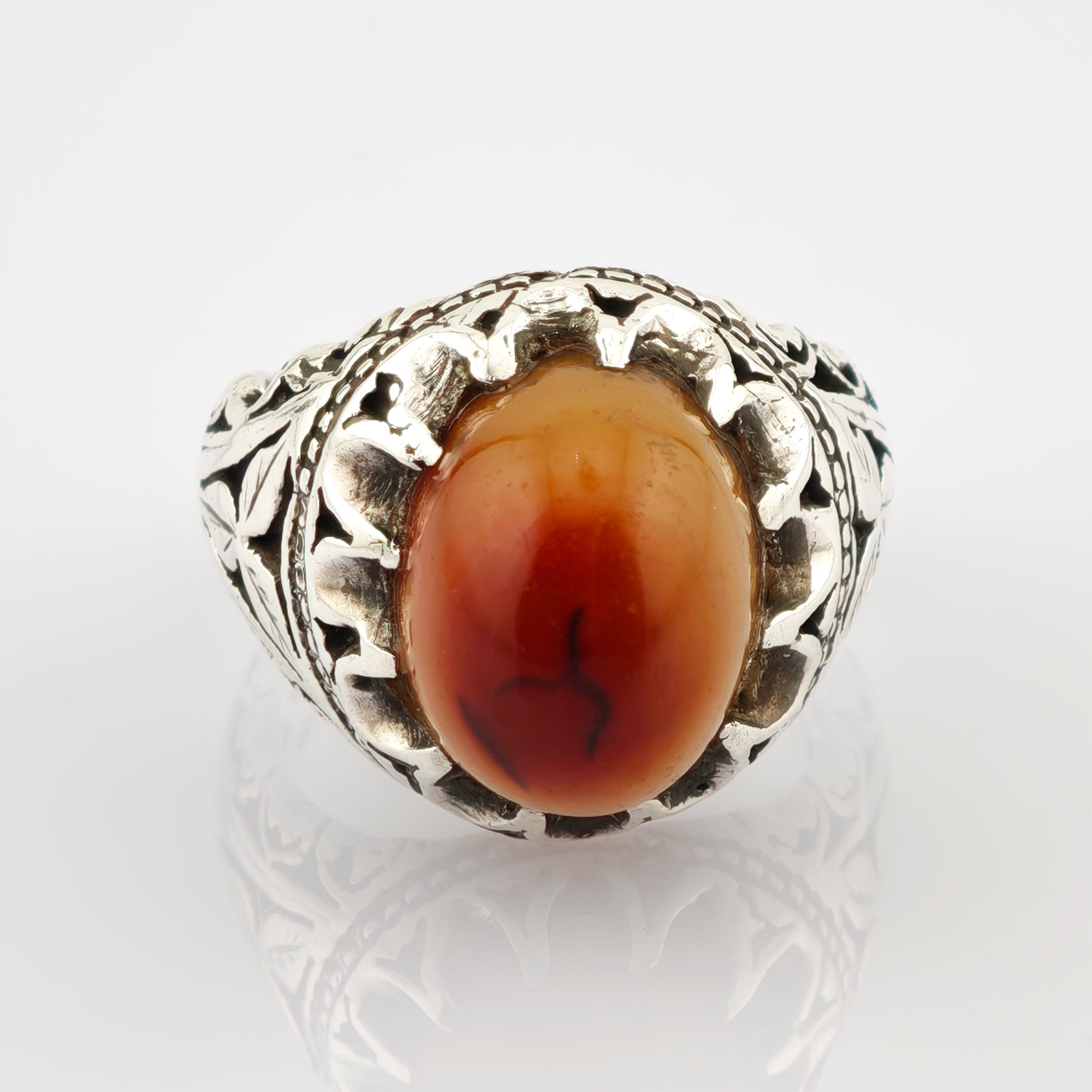 Eleganter Silberring mit ovalem rot-orangefarbenem Stein und filigranem Blatt- und Rankenmuster.