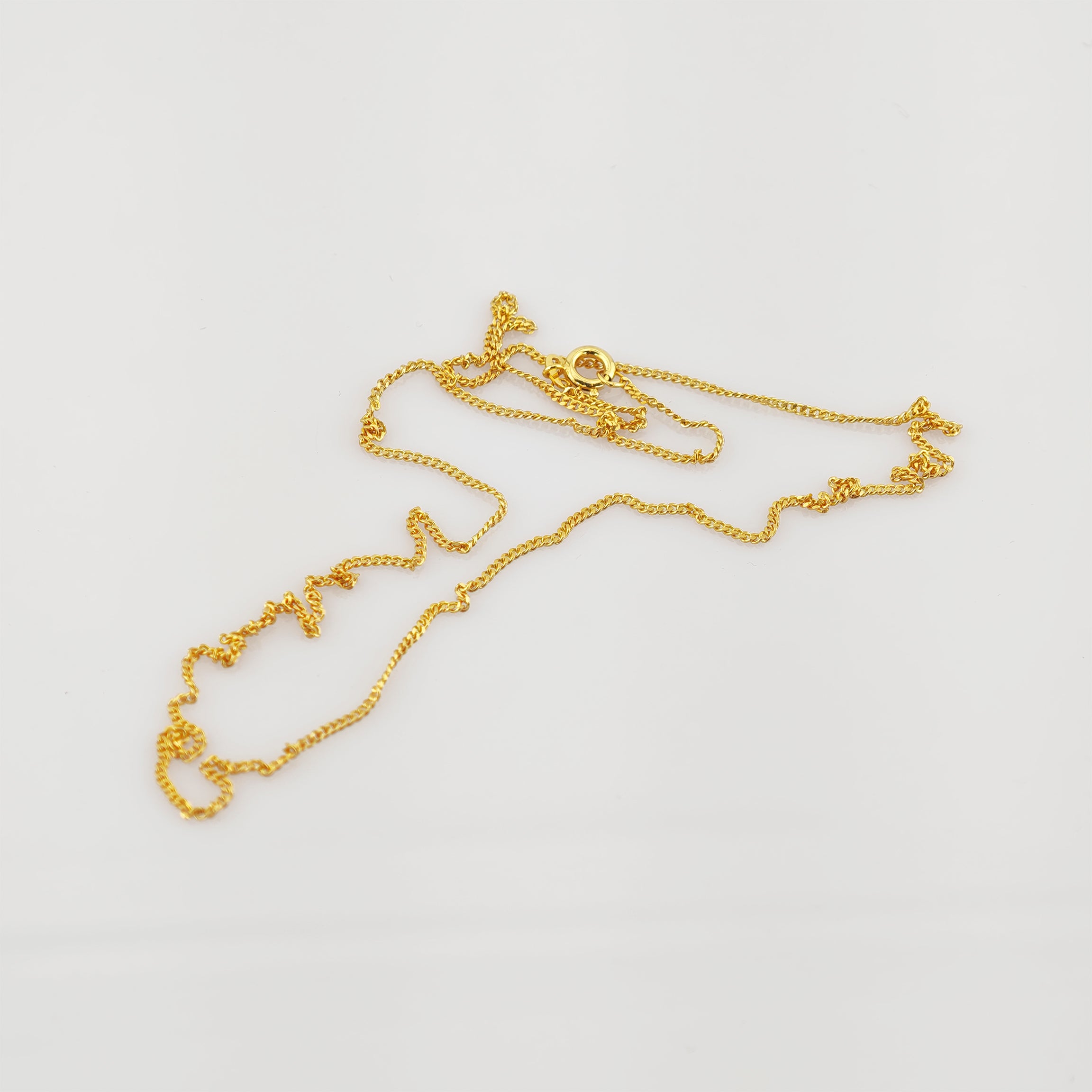 Fein gearbeitete Goldkette mit rundem Verschluss auf schlichtem weißem Hintergrund