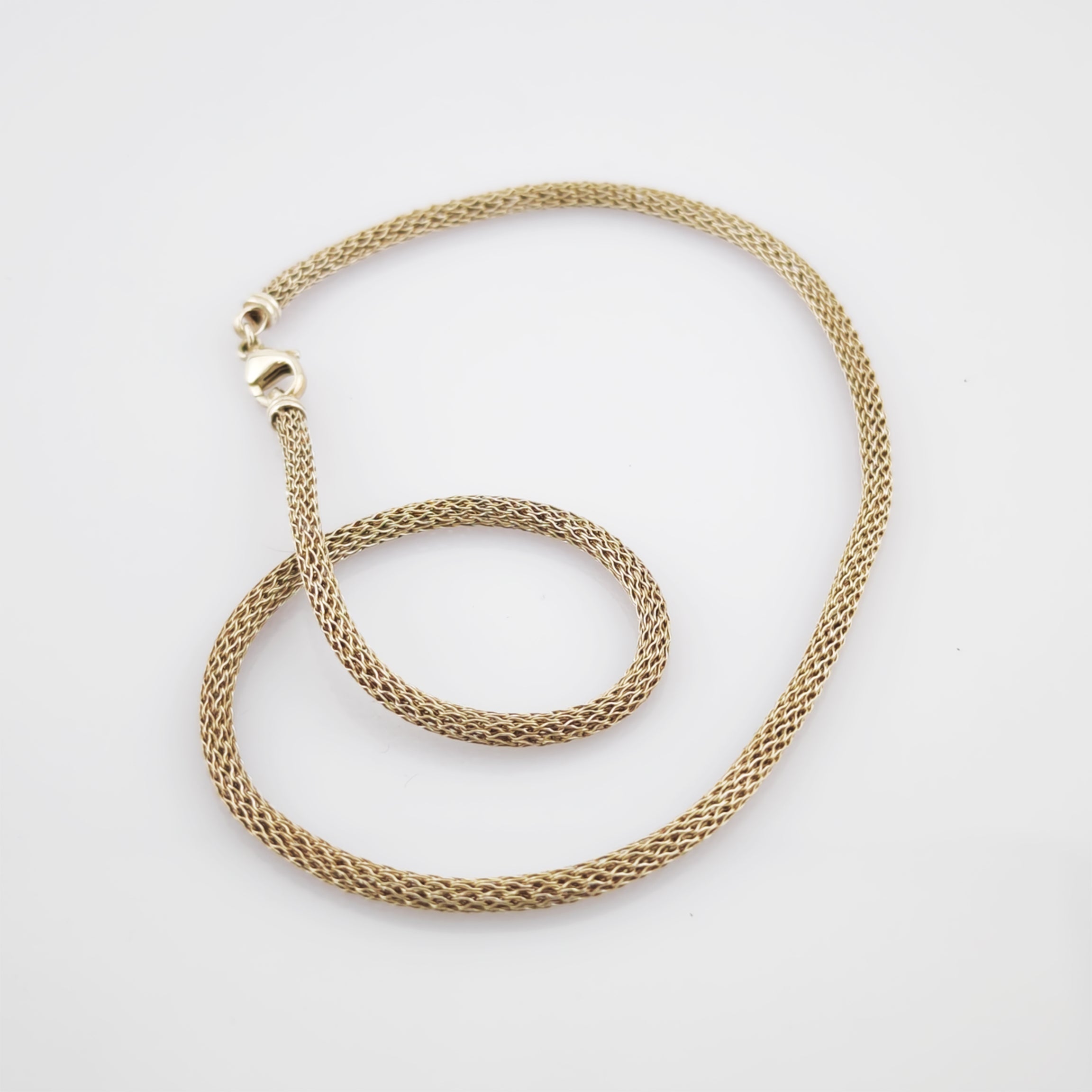 Feine Goldkette mit Diamantmuster und massivem Karabinerverschluss auf weißem Hintergrund.