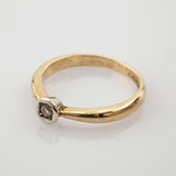 Feiner Goldring mit kleinem rundem Diamanten in silberner Fassung auf weißem Hintergrund