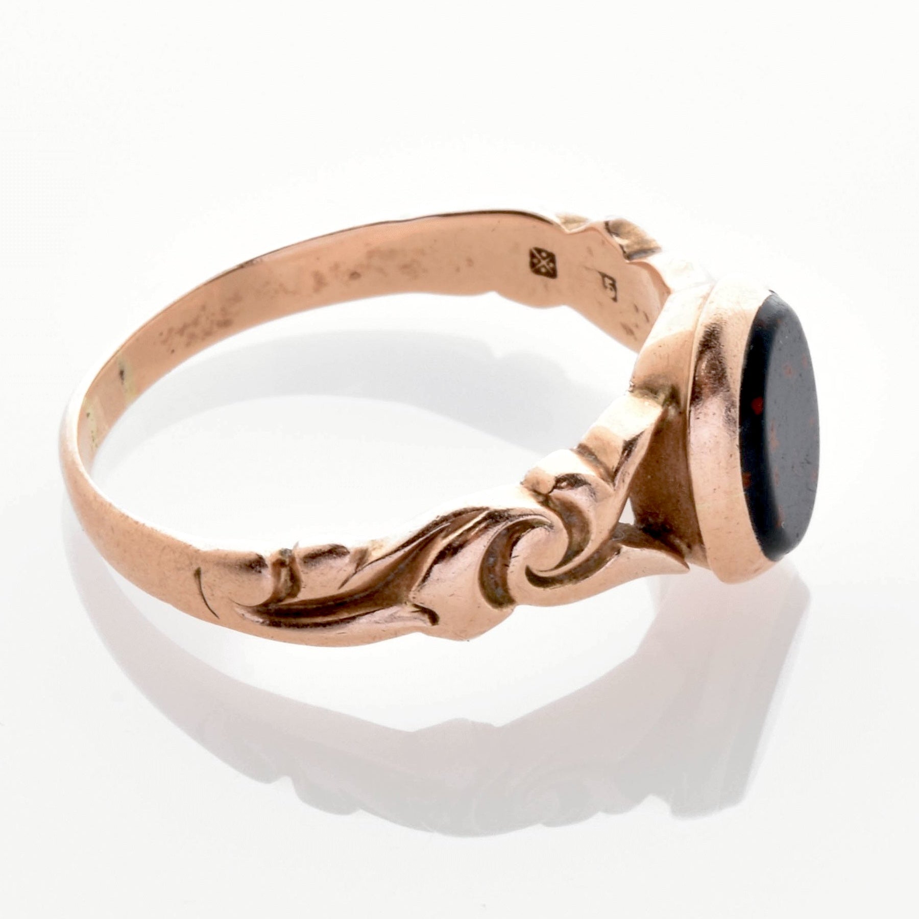 Feiner Vintage-Ring aus Gold mit kunstvollen Wirbelmustern und ovalem dunklem Stein in der Mitte.
