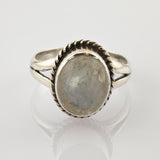 Detaillierter Silberring mit geteiltem Ringband auf reflektierender weißer Oberfläche.