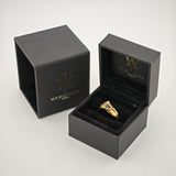 Geöffnete schwarze Schmuckboxen mit Goldlogo und goldenem Ring auf schwarzem Samt.