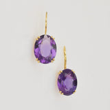 Elegante goldene Ohrringe mit ovalen violetten Edelsteinen in Goldfassung.