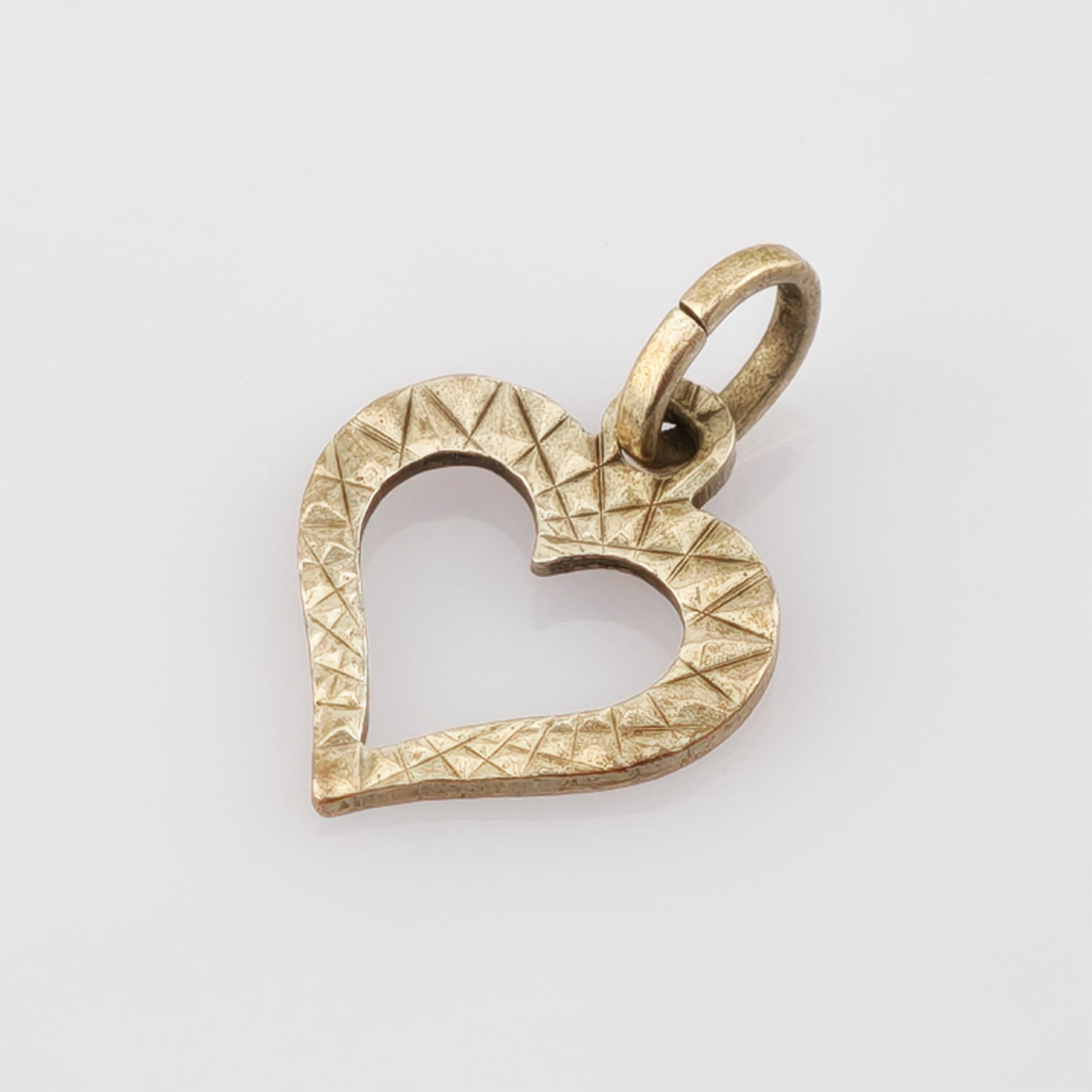 Goldener herzförmiger Anhänger mit geometrischem Dreiecksmuster und kleinem Ring zur Befestigung an einer Kette.