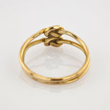 Goldener Ring mit doppeltem Band und zentralem Knoten auf weißem spiegelndem Hintergrund
