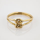 Goldener Ring mit Doppelband und zwei verflochtenen Knoten, minimalistisch und elegant.