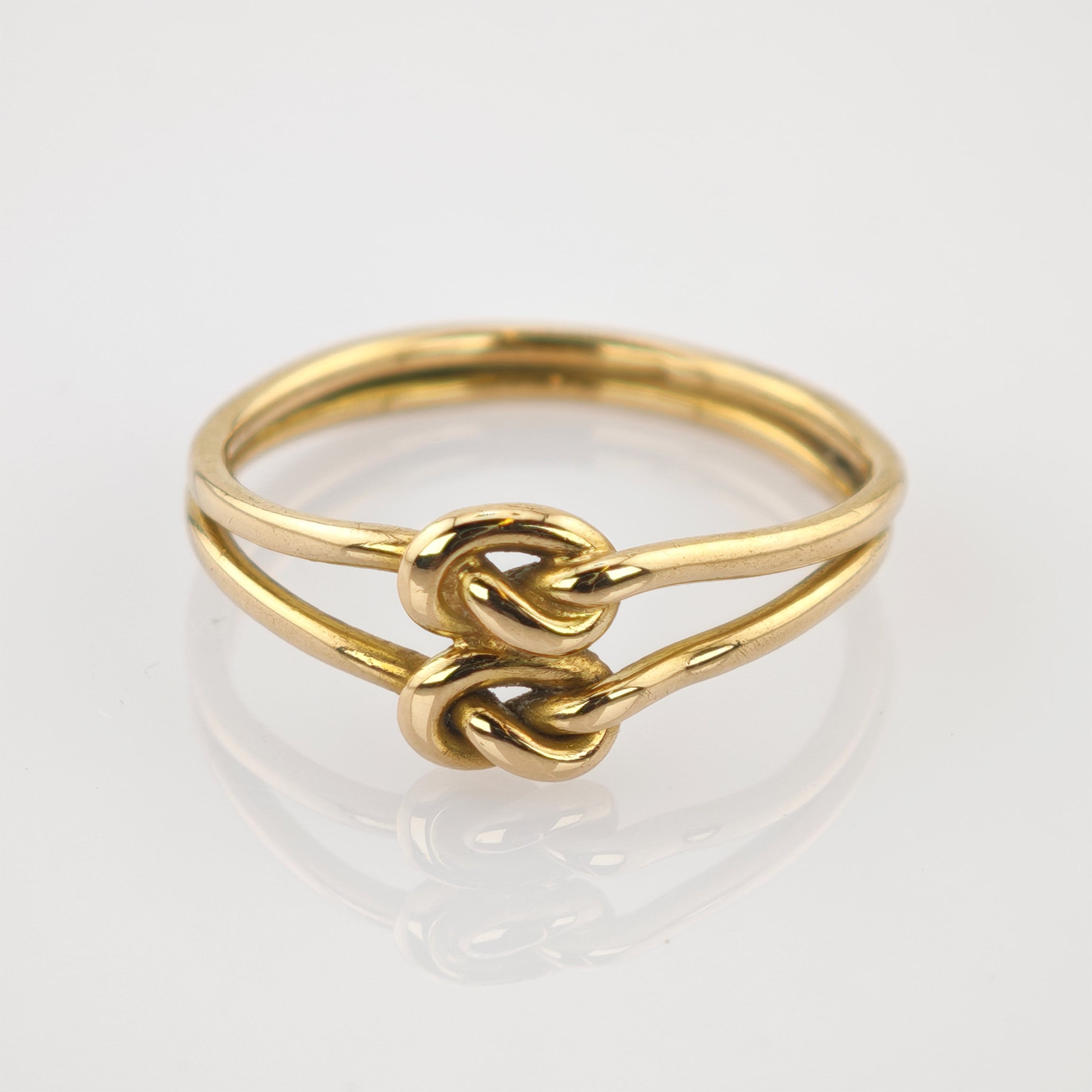Goldener Ring mit Doppelband und zwei verflochtenen Knoten, minimalistisch und elegant.