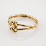 Goldener Ring mit doppeltem Drahtdesign und zwei verschlungenen Schlaufen auf weißem Hintergrund.