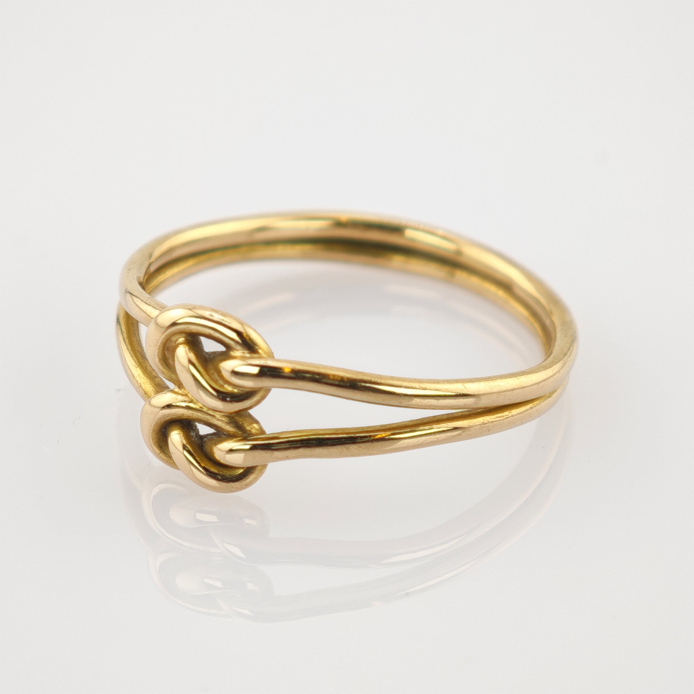 Goldener Ring mit doppeltem Drahtdesign und zwei verschlungenen Schlaufen auf weißem Hintergrund.