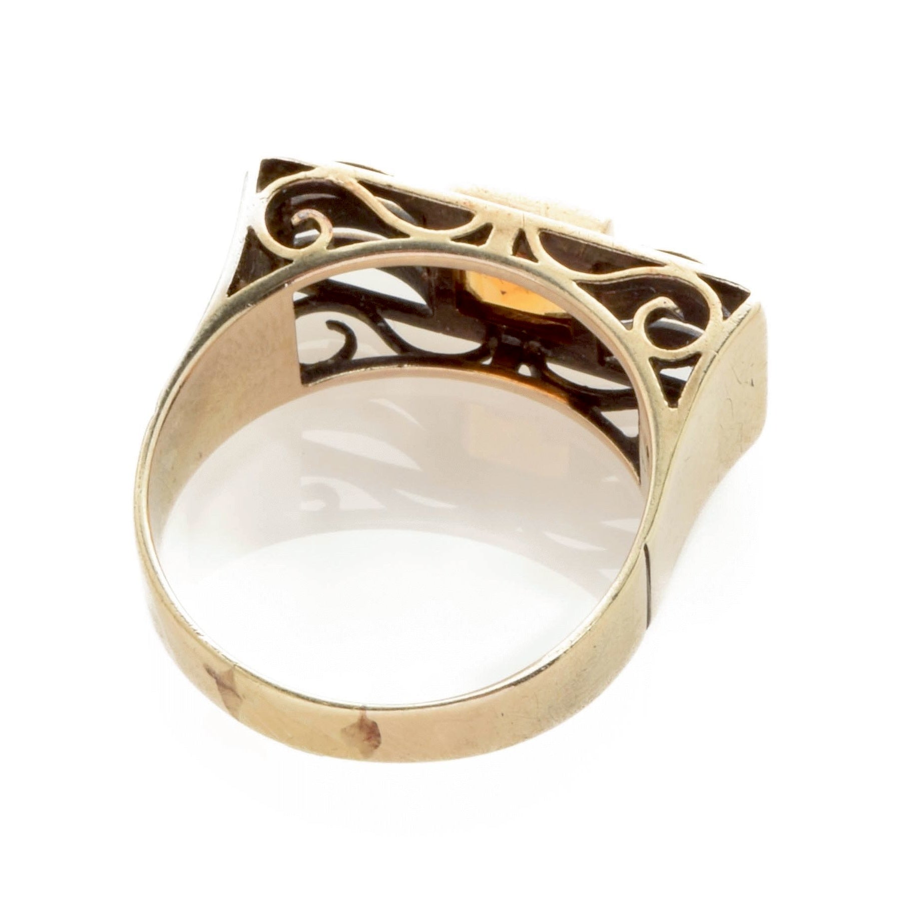 Nahaufnahme eines goldfarbenen Rings mit filigranem Muster und glattem Band