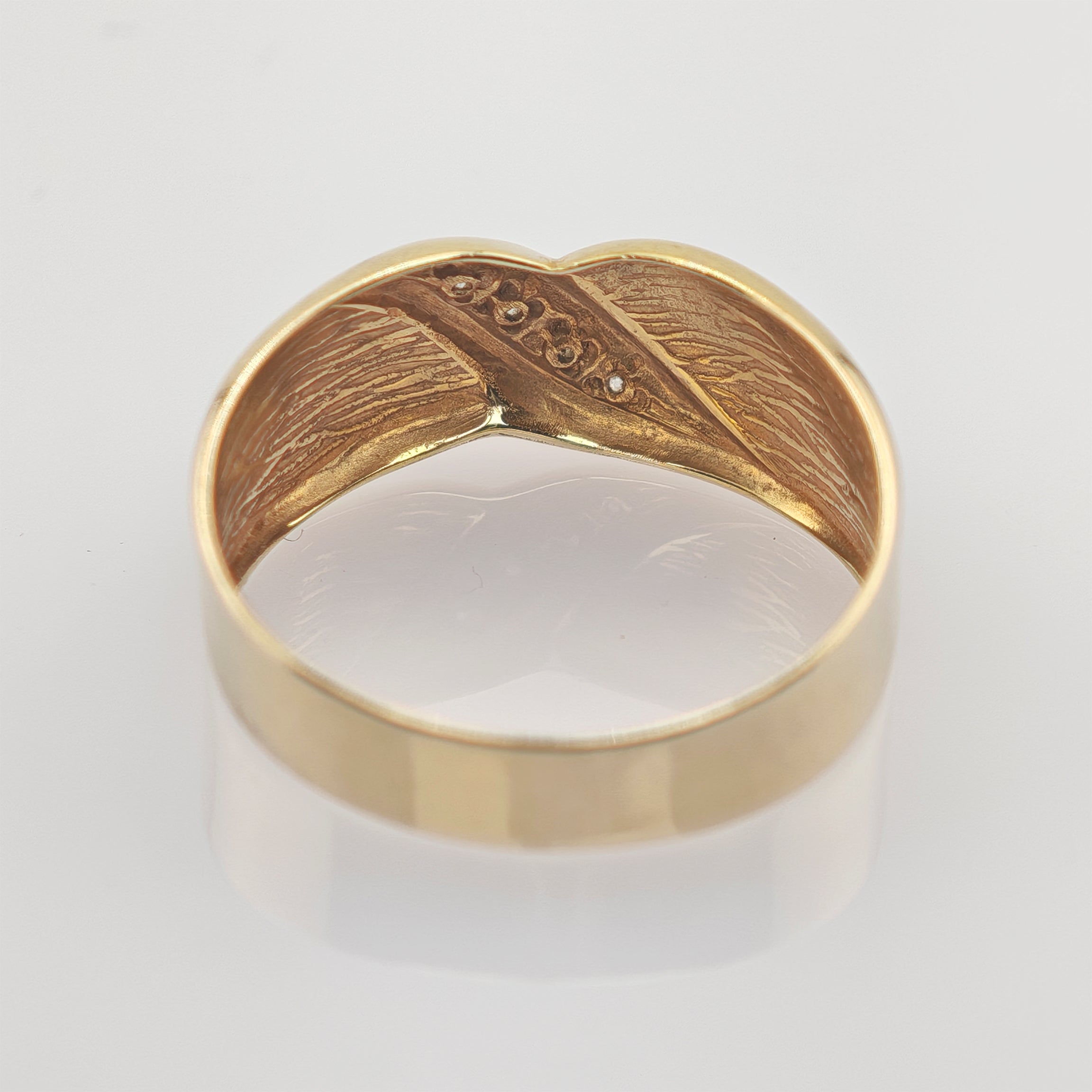 Goldener Ring mit glatter Außenseite und verzierter Innenseite mit feinen Gravuren und kleinen Steinen.
