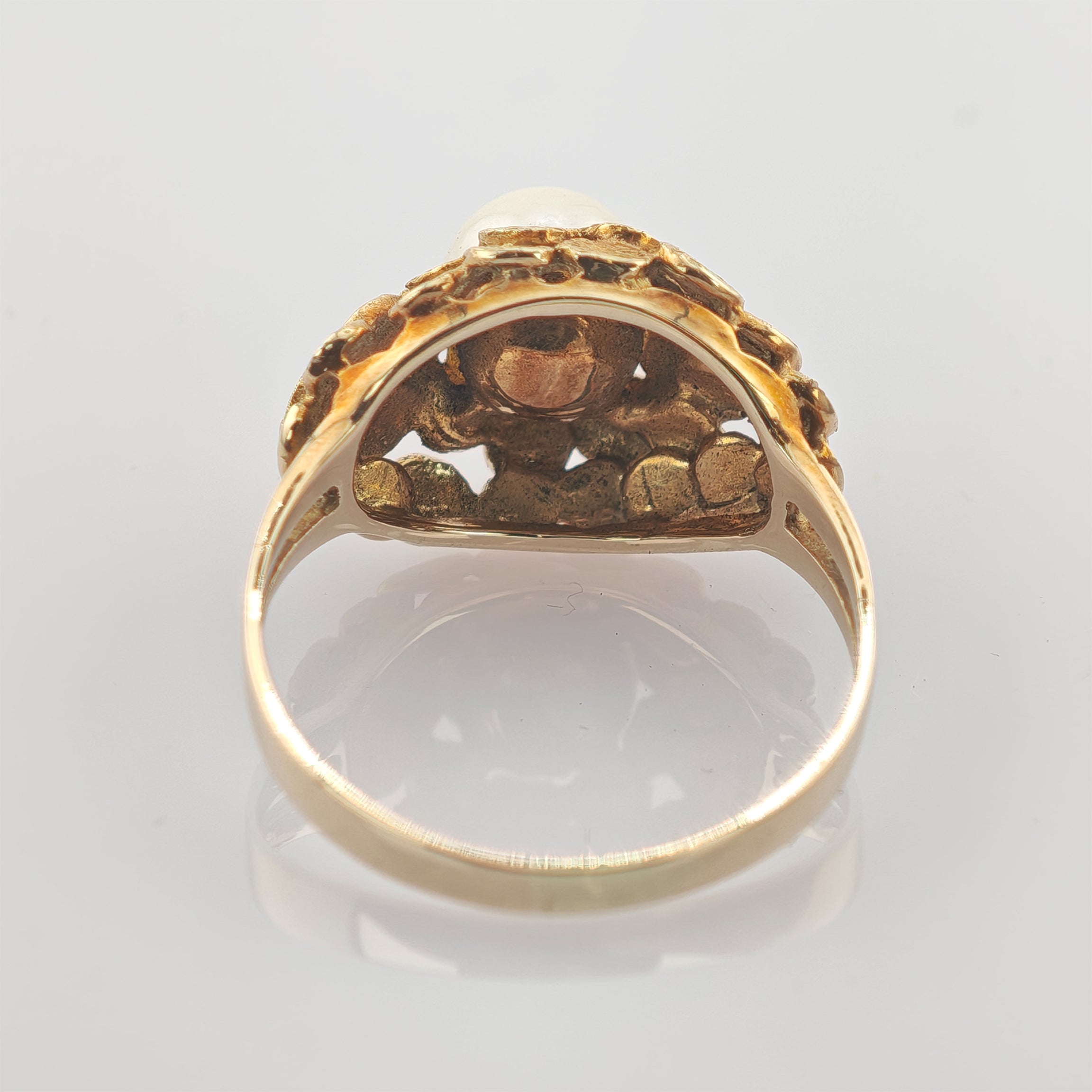 Innenansicht eines goldenen Rings mit feiner Verzierung und strukturiertem Design nahe der Fassung.