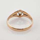 Nahaufnahme eines goldenen Rings mit klarem Edelstein in Krappenfassung auf weißem Hintergrund.