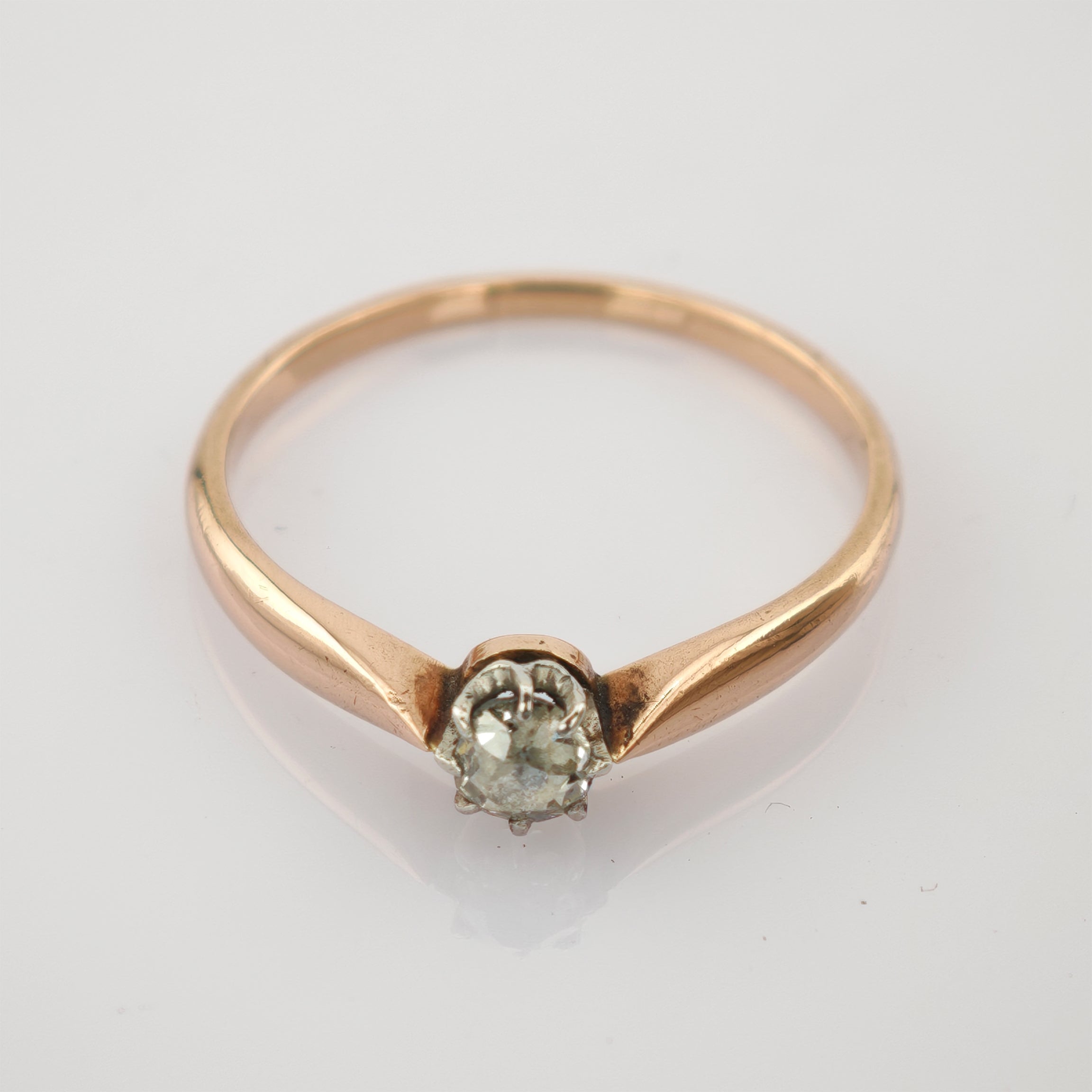 Goldener Ring mit klarem Einzelstein in Drahtfassung auf schlichtem Hintergrund