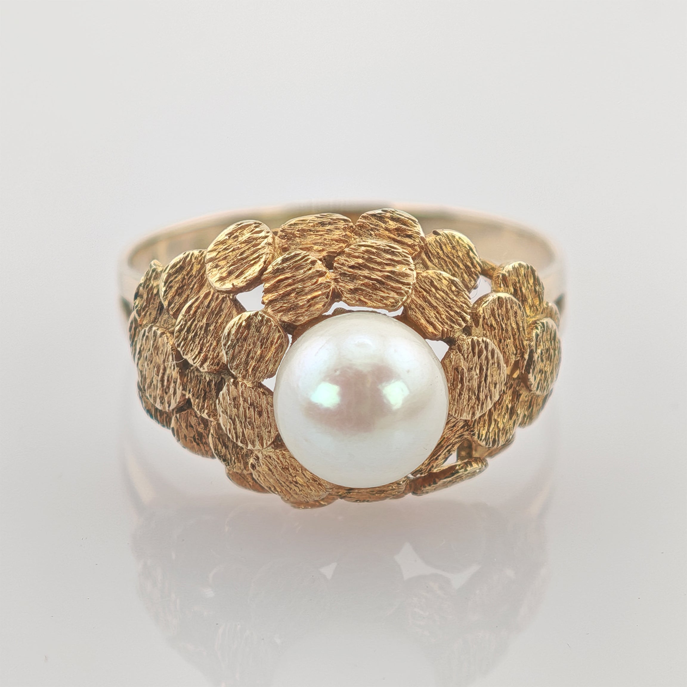 Goldener Ring mit texturierten Kreisen und einer großen weißen Perle in der Mitte