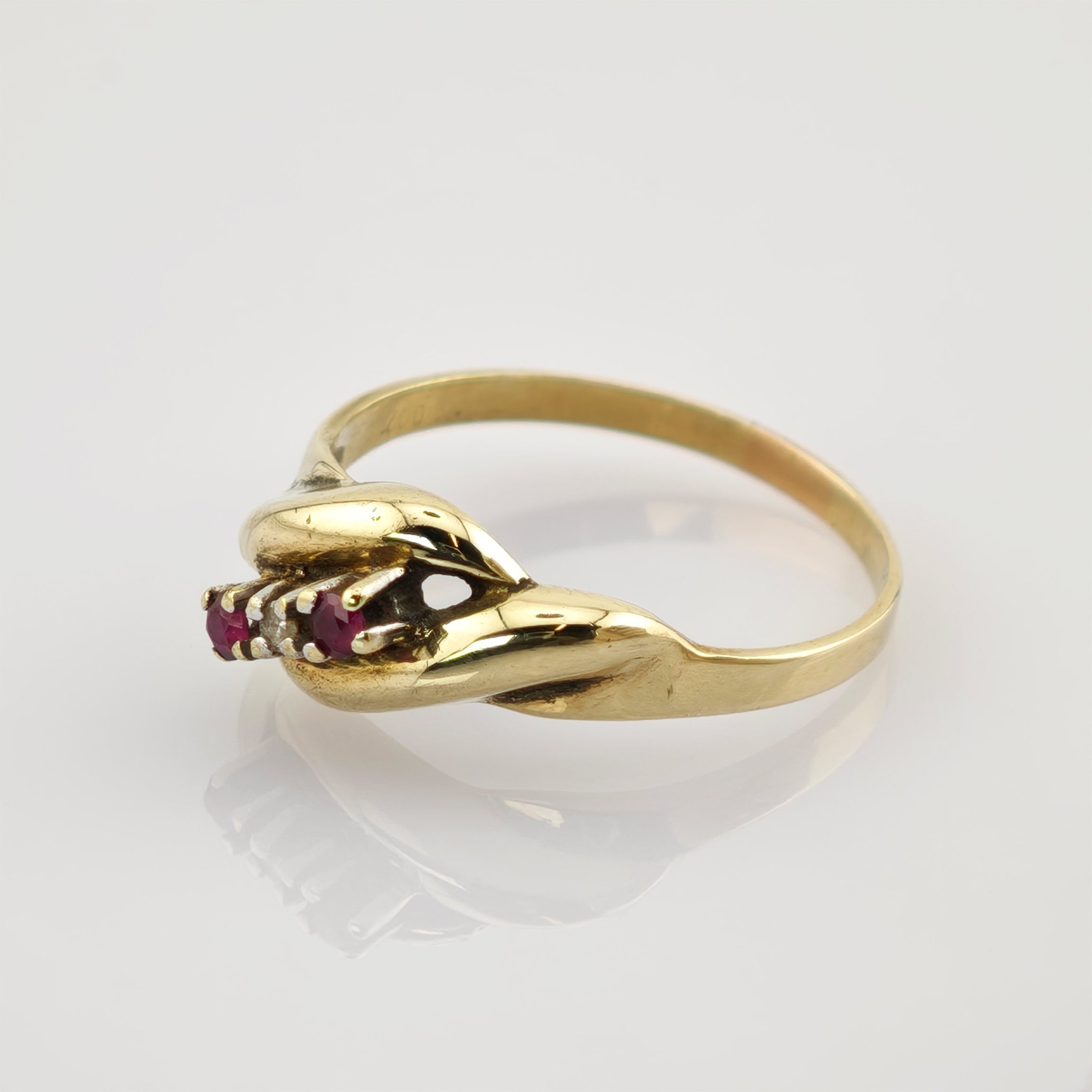 Goldener Ring mit künstlerischem Design zweier Hände, die drei kleine rote Rubine halten