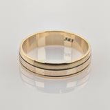 Goldener Ring mit mittlerer Rille auf glatter Oberfläche mit Spiegelung.