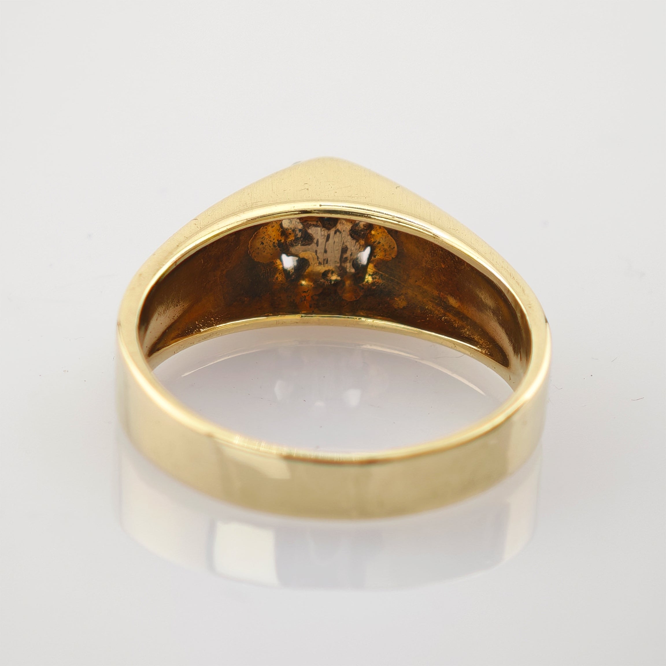 Goldener Ring mit polierter Außenseite und leicht angelaufener Innenseite auf reflektierendem weißem Untergrund.