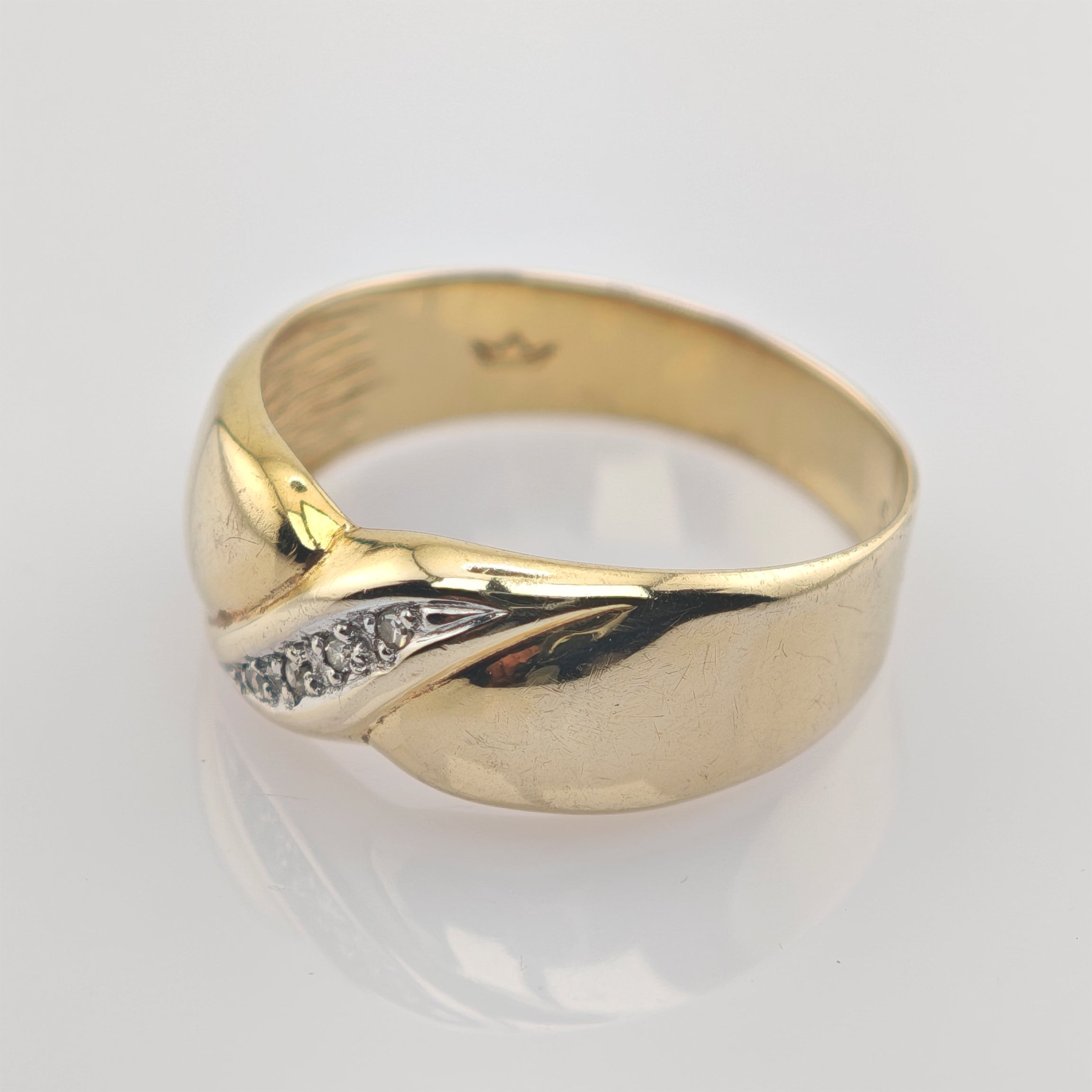 Goldener Ring mit polierter Oberfläche und silberner Einlage mit funkelnden Steinen in Blattform