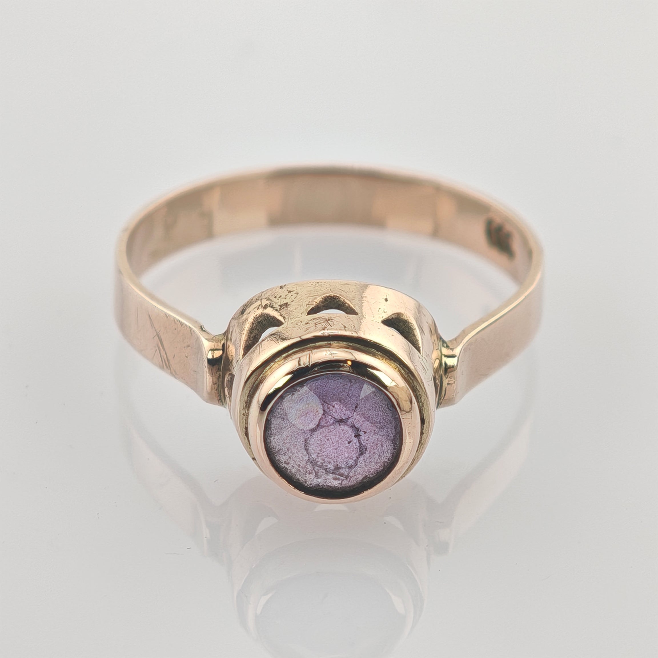 Goldener Ring mit rundem lila Stein und zarter Fassung, zeigt feine Struktur und Vintage-Charakter.