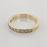 Goldener Ring mit sieben runden klaren Steinen auf reflektierendem weißen Hintergrund