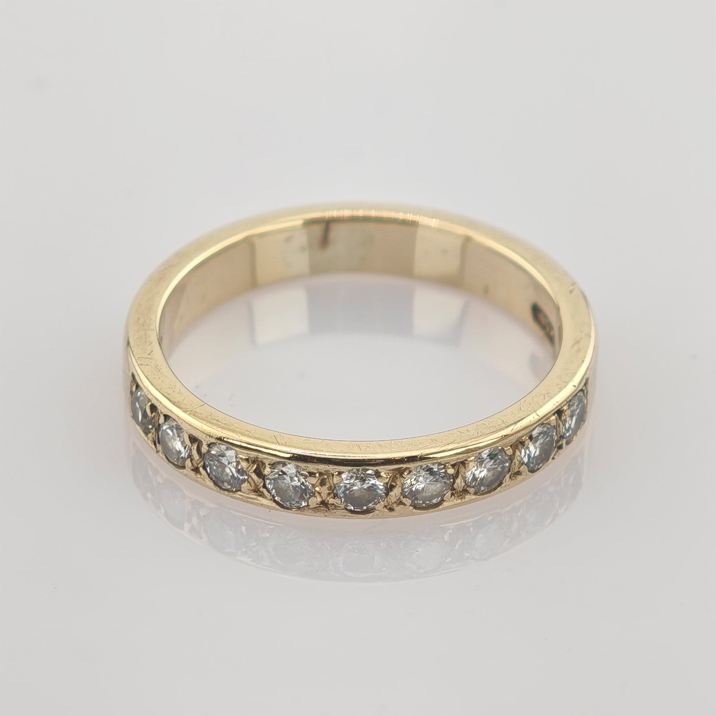 Goldener Ring mit zehn kleinen runden Diamanten auf polierter 14k-Oberfläche mit subtiler Spiegelung.