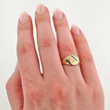 Goldener Siegelring mit eingraviertem B und blauen sowie schwarzen Emaille-Diagonallinien am linken Ringfinger