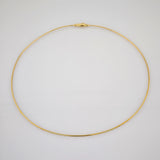 Zarte goldfarbene Halskette mit feiner Kettengliederung und Karabinerverschluss auf grauem Hintergrund