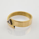 Goldfarbener Ring mit flacher Ringschiene und dreieckigem Designelement mit klarem Edelstein.