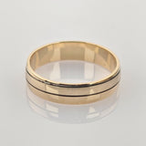 Goldfarbener Ring mit polierter Oberfläche und zwei dünnen parallelen Rillen auf spiegelnder weißer Fläche