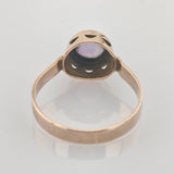 Goldfarbener Vintage-Ring mit rundem violettem Edelstein und dekorativer Fassung auf weißem Hintergrund