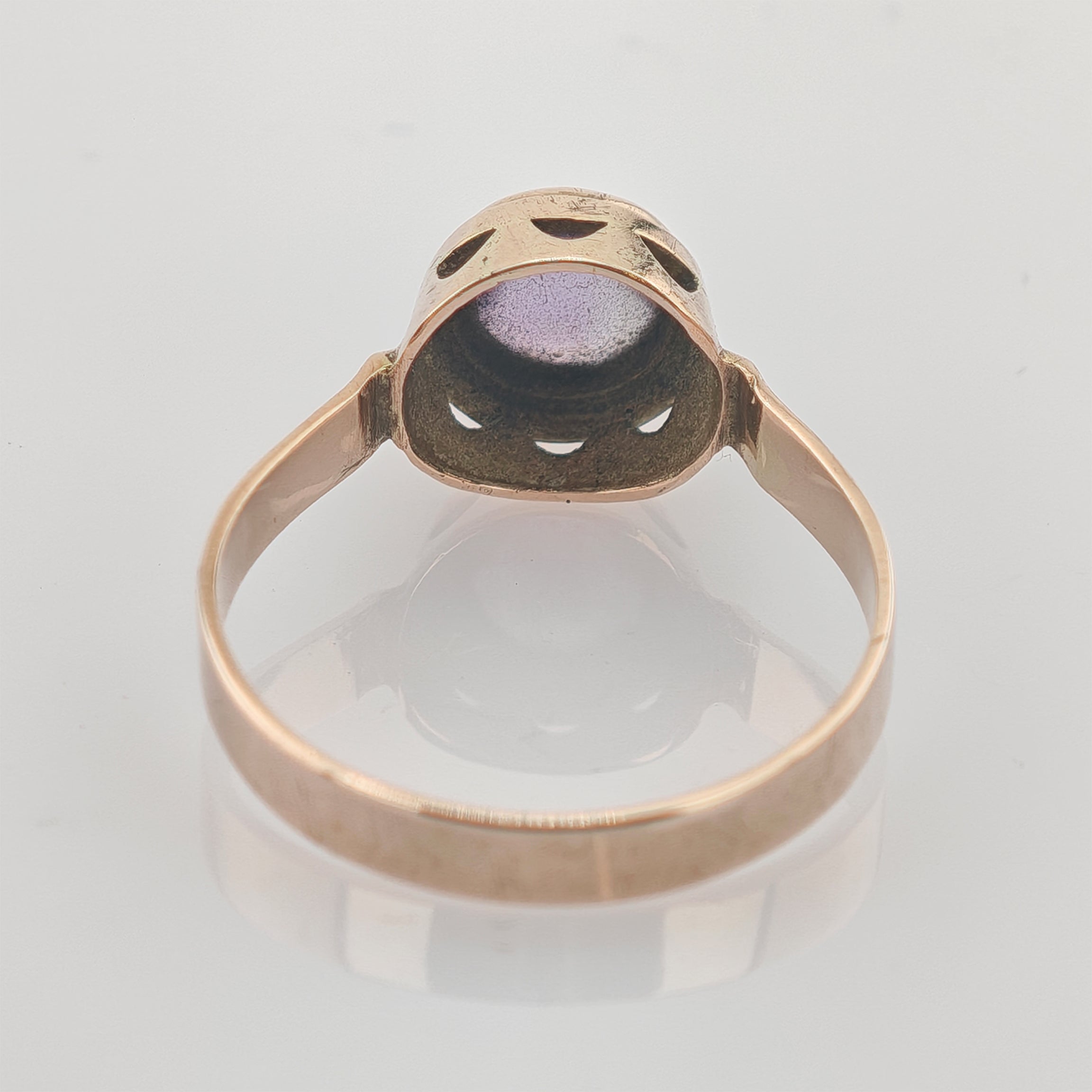 Goldfarbener Vintage-Ring mit rundem violettem Edelstein und dekorativer Fassung auf weißem Hintergrund